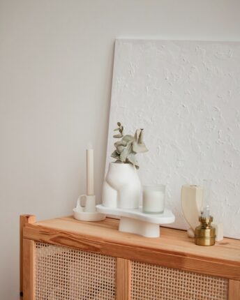 a white vase sitting on top of a wooden cabinet
