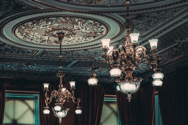 two gold-colored chandeliers on ceiling inside room