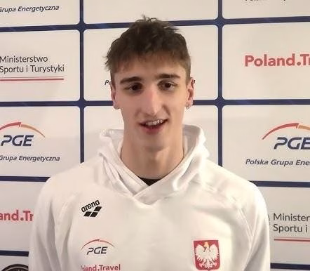 Zbliżenie na twarz Ksawerego Masiuka podczas intensywnego wyścigu stylem grzbietowym, ukazujące jego determinację i skupienie.