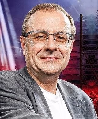 Profesor Antoni Dudek przy biurku, otoczony książkami.